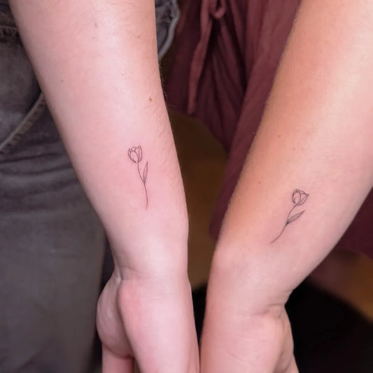Tiny Fine Line Tulip Tattoo on Women Forearm by @elizatattooamsterdam