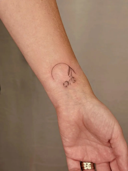 Tiny Fine Line Tulip Tattoo on Women Wrist by @aria.inkart
