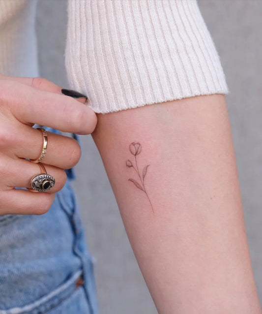 Tiny Fine Line Tulip and Stem Tattoo on Women Forearm by @stefano__mazza