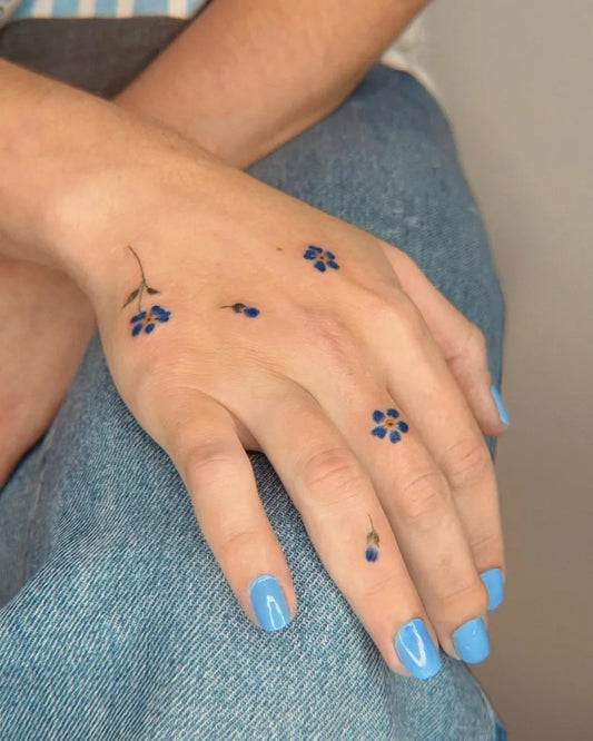 Tiny Floral Blue Flowers and Paw Prints on Women Fingers Tattoo by @eva_tattooist