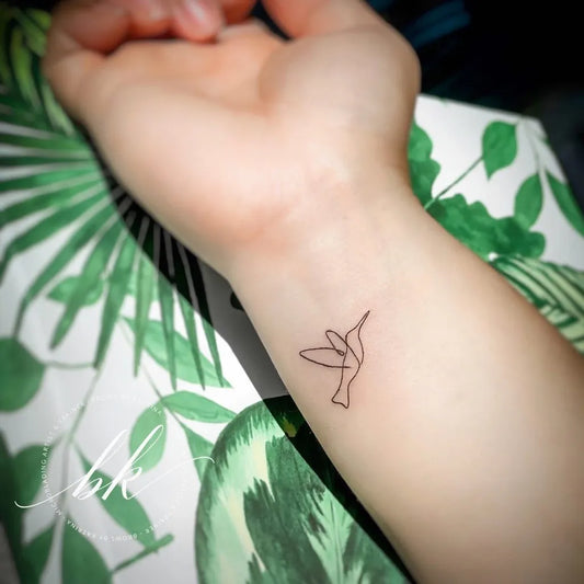 Tiny Linework Hummingbird on Women Wrist Tattoo by @browsbykatrinallc