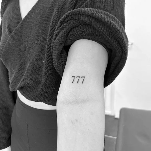 Tiny Minimalist 777 Tattoo on Women Upper Arm by @finelinesbyanesha