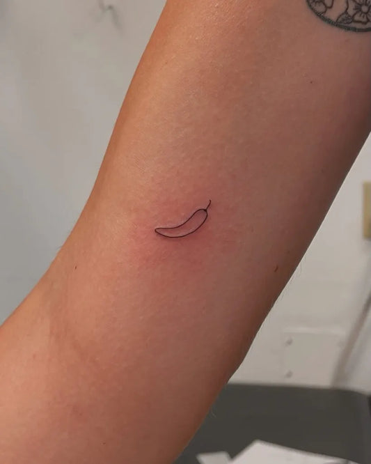 Tiny Minimalist Banana Pepper on Women Arm Tattoo by @arimika.tattoo