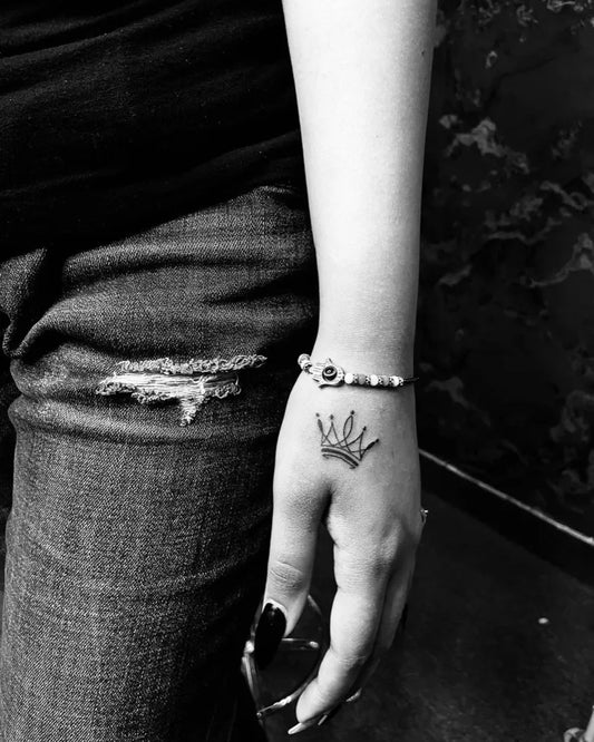 Tiny Minimalist Crown Tattoo on Women Hand by @parleeninks