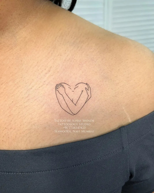 Tiny Minimalist Heart Hug on Women Shoulder Tattoo by @tattoology_studio
