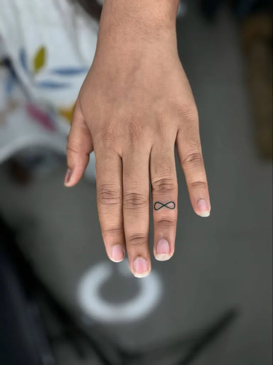 Tiny Minimalist Infinity Tattoo on Women Finger by @kabirainktattooandpiercing