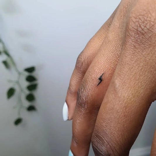 Tiny Minimalist Lightning Bolt Tattoo on Women Finger by @c.knight_tattoo