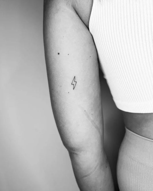 Tiny Minimalist Lightning Bolt Tattoo on Women Upper Arm by @j.h.ditchfield_tattoo