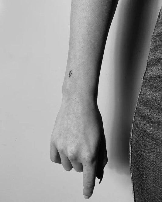 Tiny Minimalist Lightning Bolt Tattoo on Women Wrist by @bobbie.ink