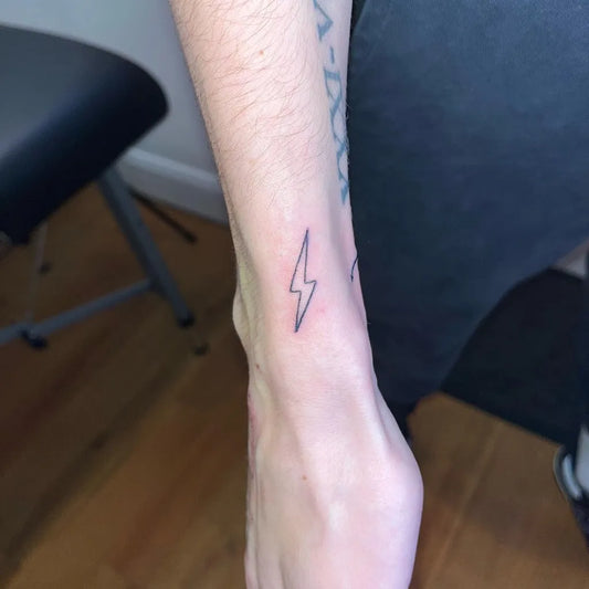 Tiny Minimalist Lightning Bolt Tattoo on Women Wrist by @hattiefaithtattooartist