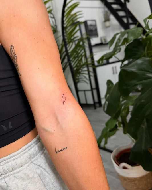 Tiny Minimalist Lightning and Word on Women Arm Tattoo by @bladesandneedles_