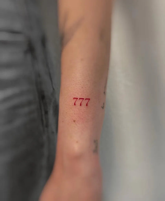 Tiny Minimalist Red 777 Tattoo on Women Arm by @kiwi.tattoo.ink