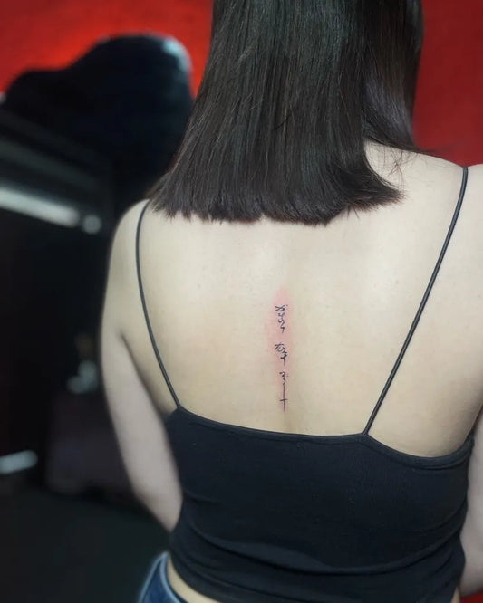 Tiny Minimalist Script Cross on Women Spine Tattoo by @donya_tattoos