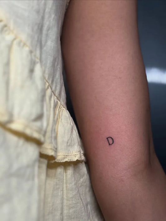 Tiny Minimalist Single Letter D on Women Arm Tattoo by @kd.inks
