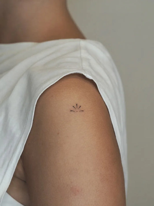Tiny Minimalist Sunburst on Women Upper Arm Tattoo by @gulcessavran