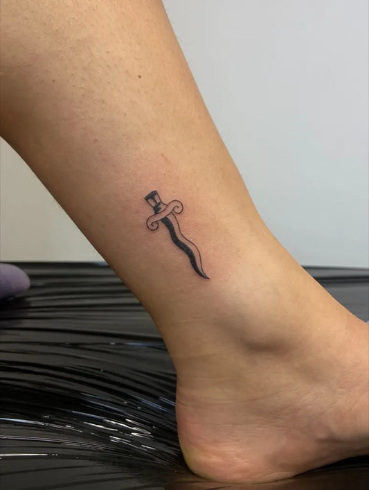 Tiny Minimalist Sword on Women Ankle Tattoo by @alleykat.tattoo