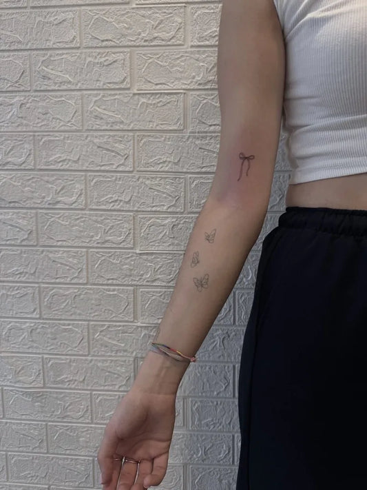 Tiny Minimalist Tau cross and dots on Women Arm Tattoo by @bali_tattoo.studio