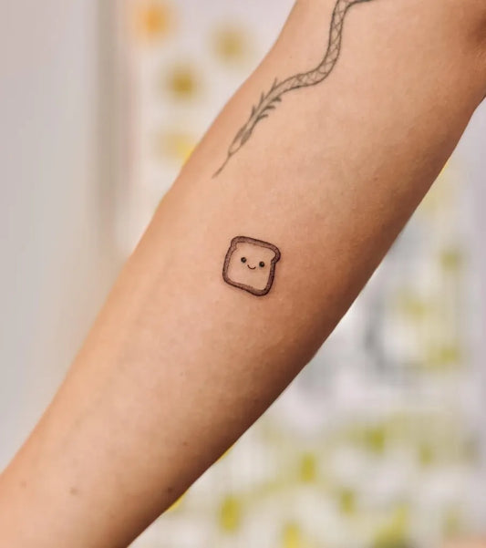Tiny Minimalist Toast and Snake on Women Arm Tattoo by @bnanatattoo