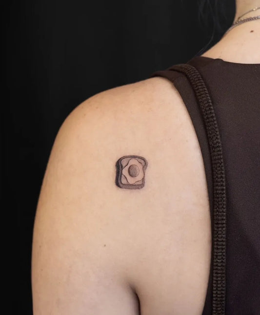 Tiny Minimalist Toast with Egg on Women Shoulder Tattoo by @flow_tattoo_toronto