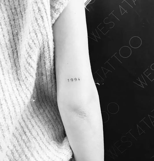 Tiny Minimalist Year Number Tattoo on Women Arm by @little.tattoos