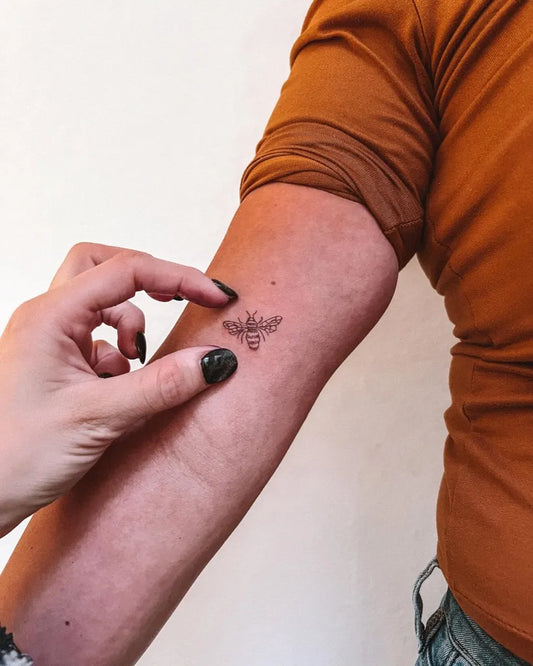 Tiny Minimalist bee on Women upper arm Tattoo by @aura.tattoo5