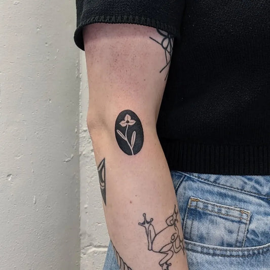 Tiny Negative Space Oval Lily Flower Tattoo on Women Elbow by @molebulle