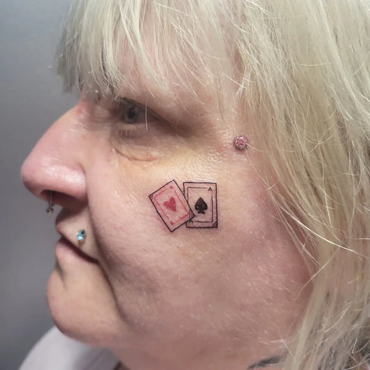 Tiny Neotraditional Queen Spades Cards on Women Face Tattoo by @miri_ink_art