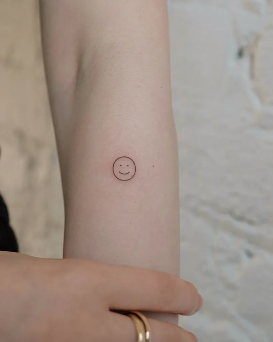 Tiny Outline Smiley Face Tattoo on Women Arm by @miko_nyctattoo