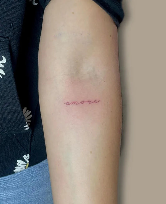 Tiny Red Script Word Tattoo on Women Arm by @tatt.elena