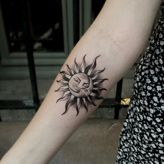 black and grey tribal sun tattoo on inner forearm