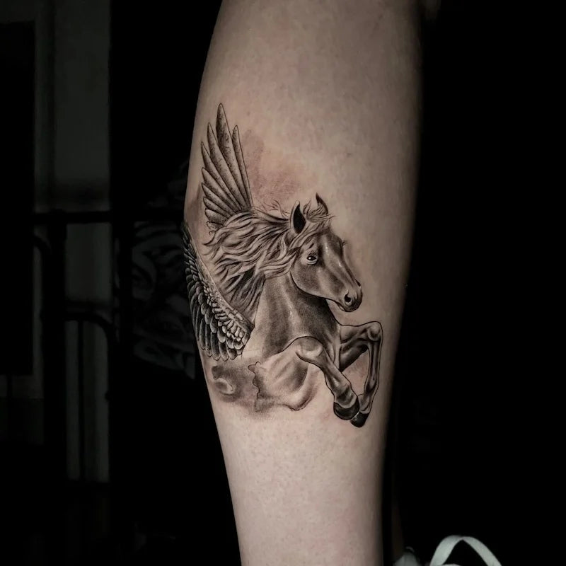 black and grey winged flying horse tattoo on forearm