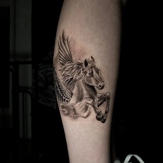 black and grey winged flying horse tattoo on forearm