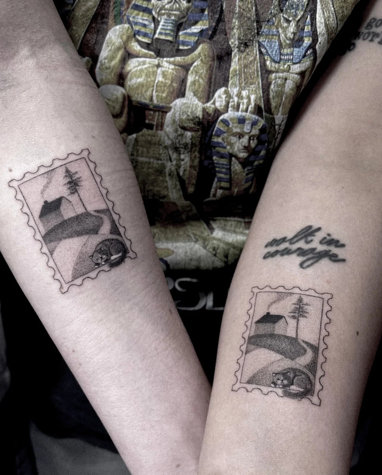 black and grey single needle dotwork matching tattoos of postage stamps with landscapes and a cat on arms