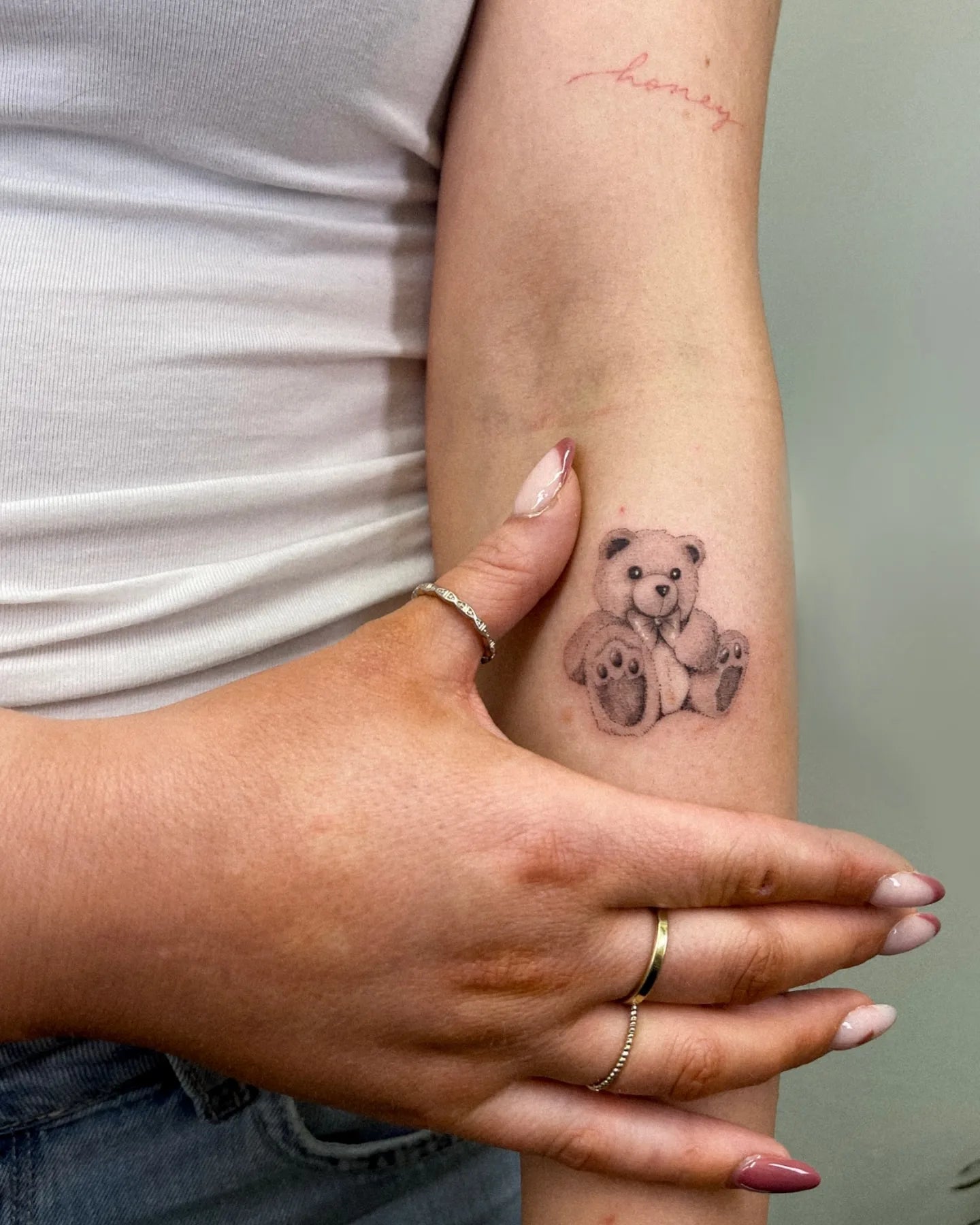 black and grey micro realism teddy bear tattoo on woman forearm