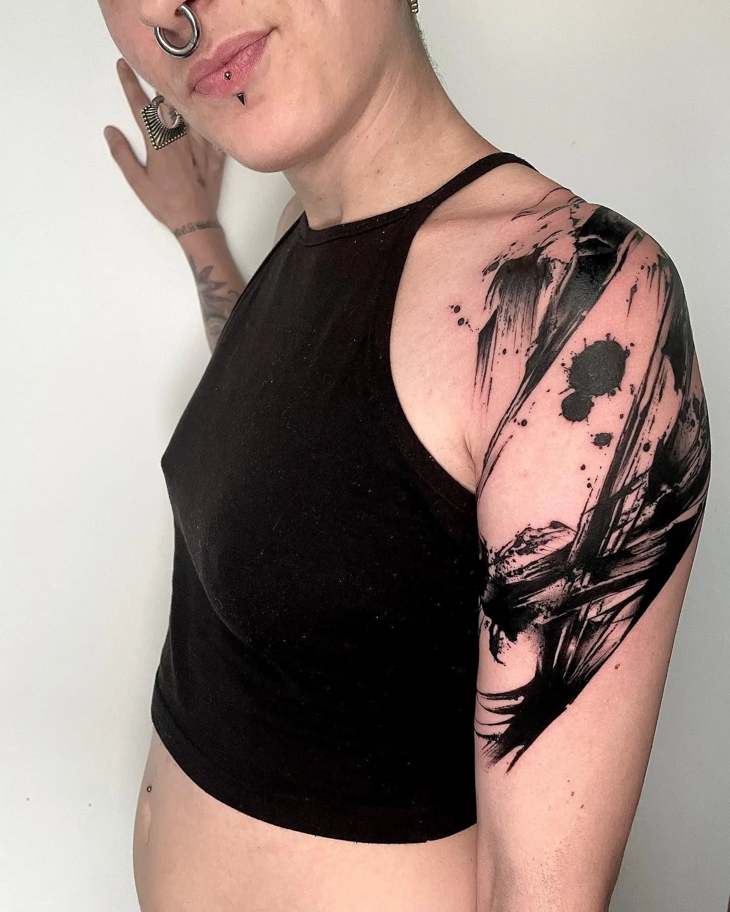 black watercolor brush stroke blackwork tattoo on woman shoulder