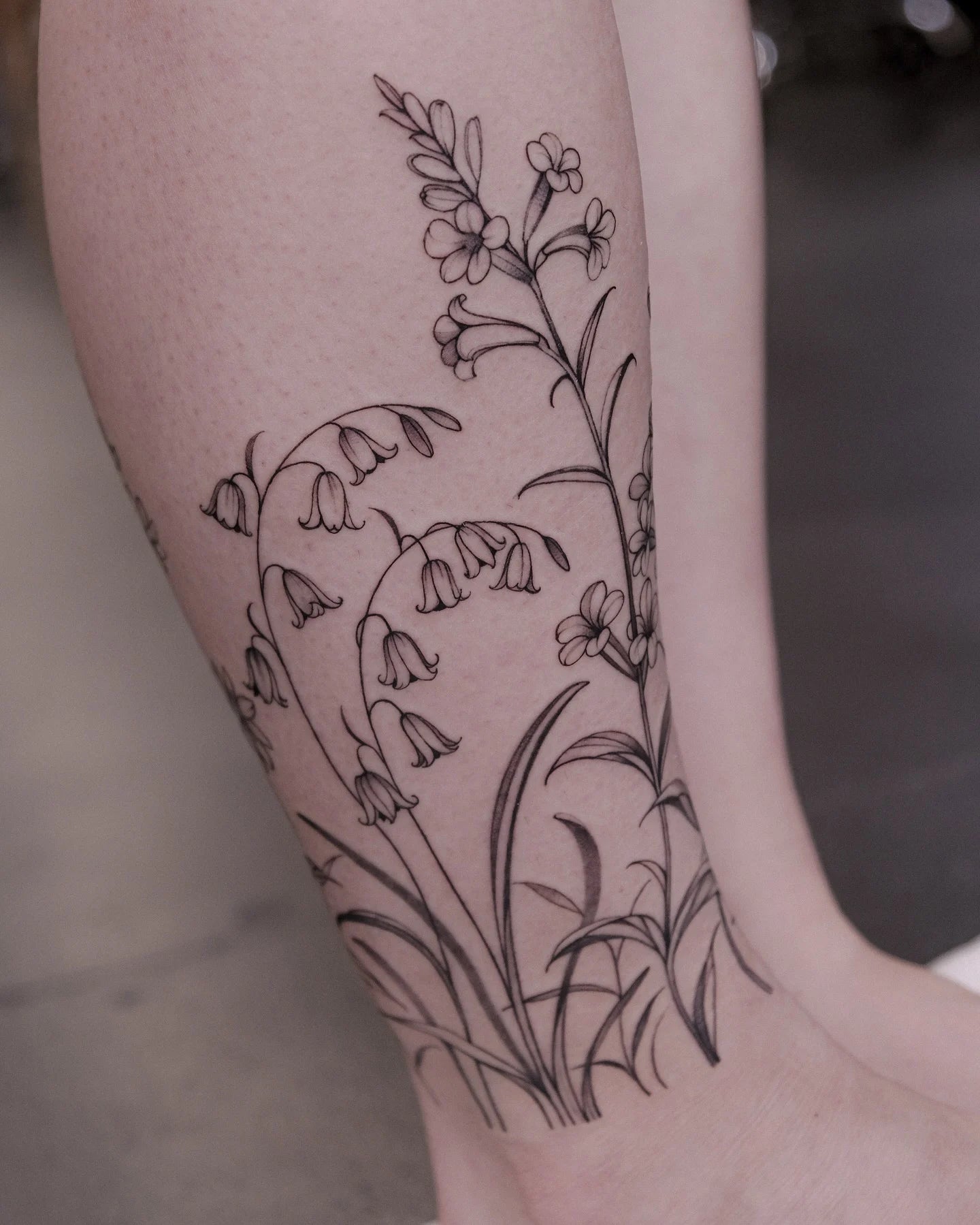 fine line floral tattoo on woman leg