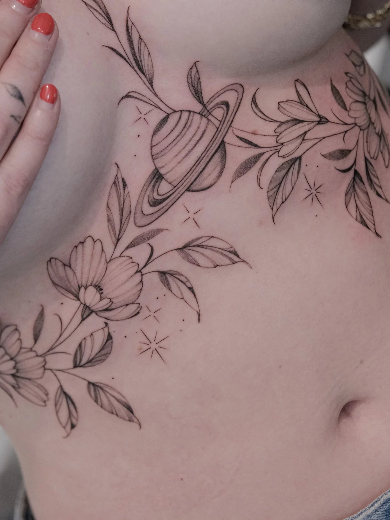 fine line flowers and planet under breast tattoo