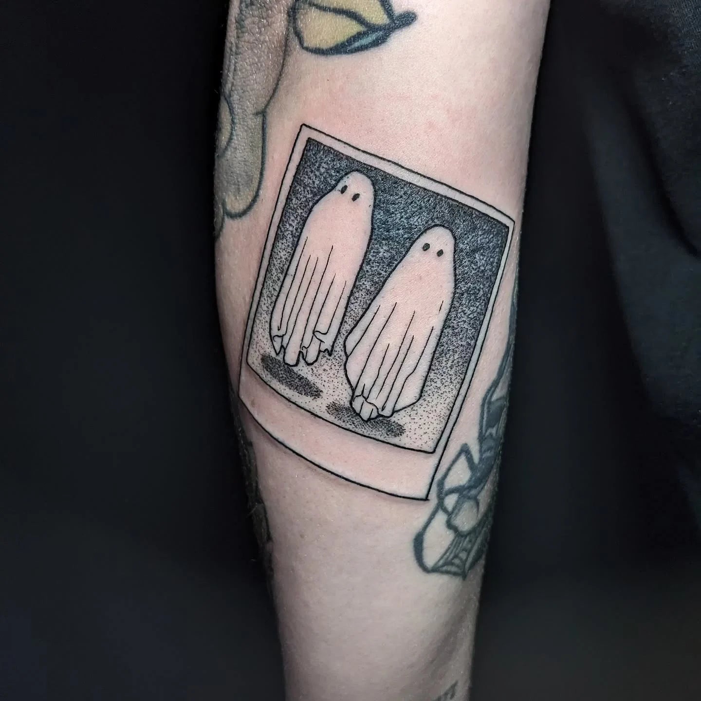 dotwork tattoo of two ghosts in a square frame on forearm