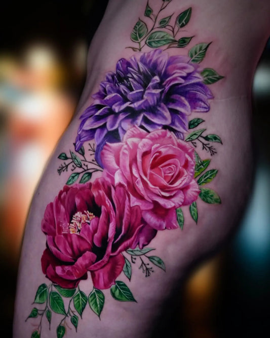 Colorful floral tattoo on hip with purple, pink, and green flowers.