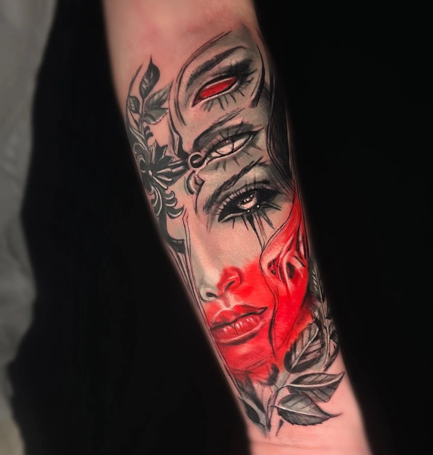 abstract woman face with red accents forearm tattoo