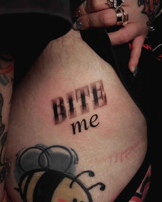 blurry bite me lettering tattoo