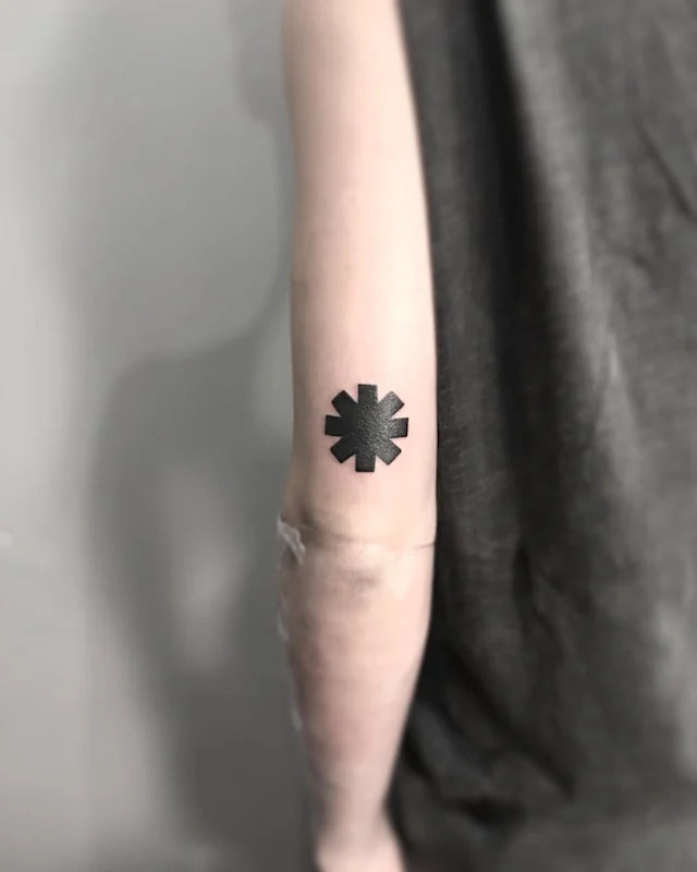 Black asterisk star blackwork tattoo on arm back red hot chilli pepper