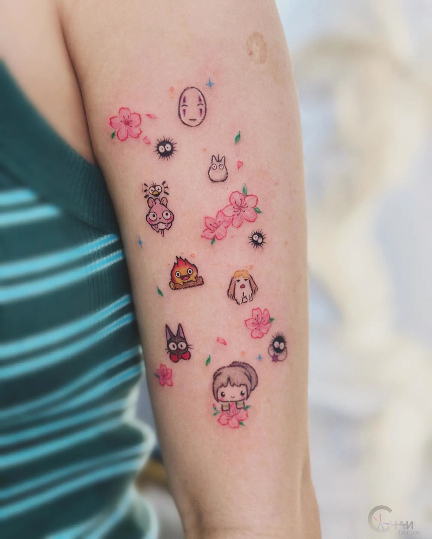 colorful minimalist small tattoos of cartoon characters and flowers on woman upper arm