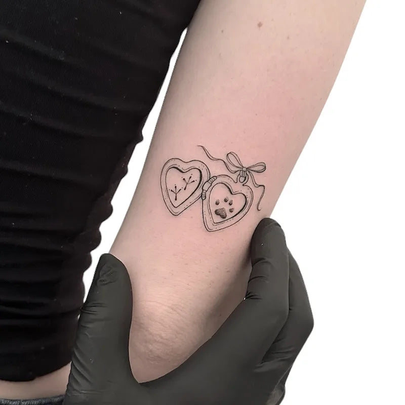 heart box with animal paw outline fine line tattoo on woman upper arm