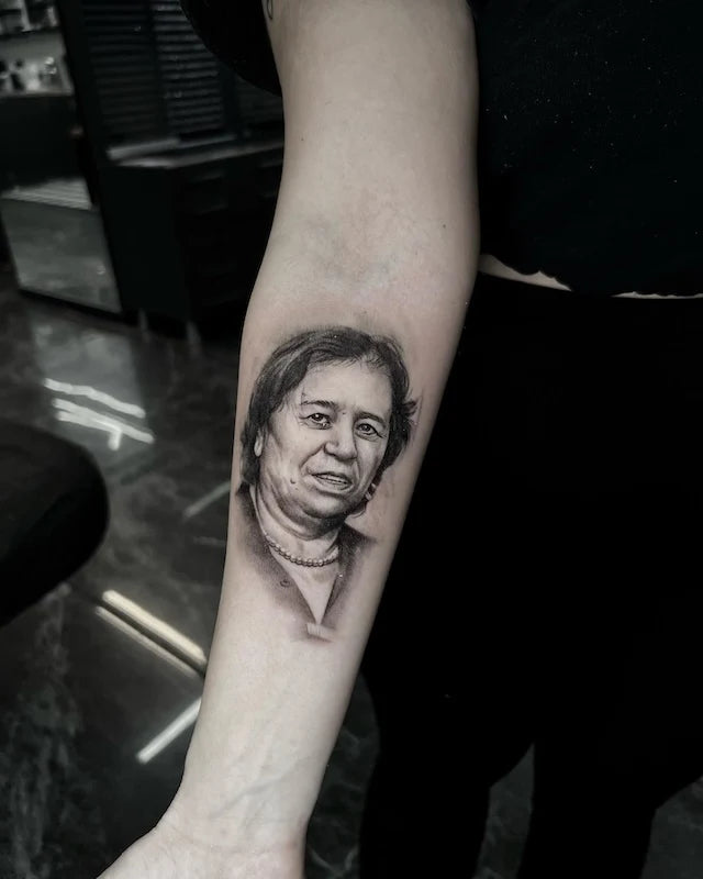 black and grey old woman portrait realism tattoo on woman inner forearm