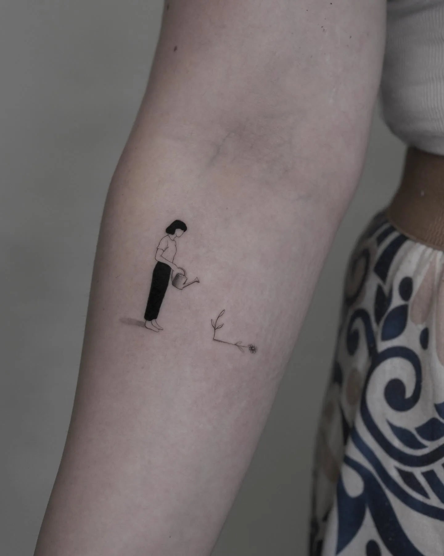 abstract illustrative minimalist woman planting tattoo on inner arm