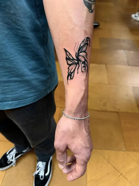 abstract blackwork twisted butterfly tattoo on man forearm