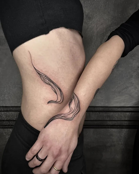 matching abstract blackwork lines tattoo on woman stomach and man wrist