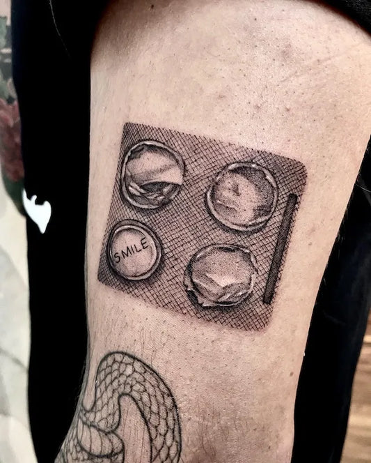 realistic black and grey smile pill drugs tattoo on man upper arm