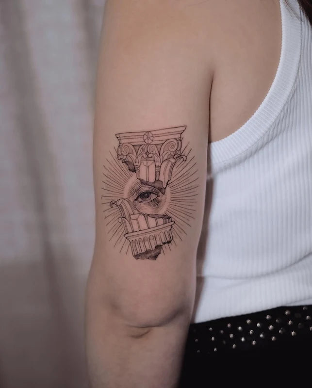 ancient greek sculpture architecture with an eye black and grey dotwork tattoo on woman back arm